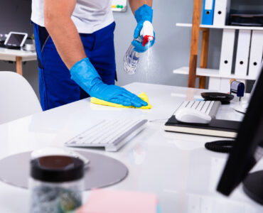 Janitor cleaning white desk in modern office